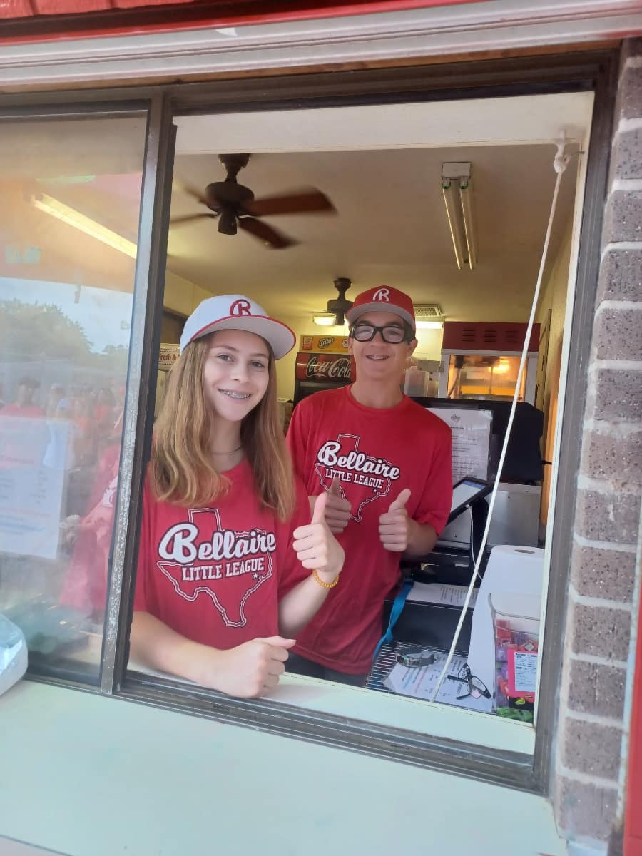 Two teens giving a thumbs up while working at concessions stand